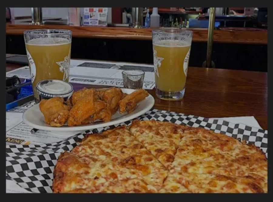 Wings, cheese pizza and two pints of beer on a bar table at the Riv